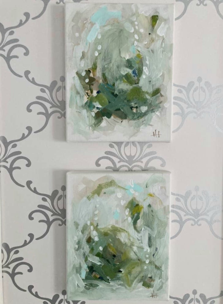 Two abstract art pieces on a decorative wall with floral patterns.