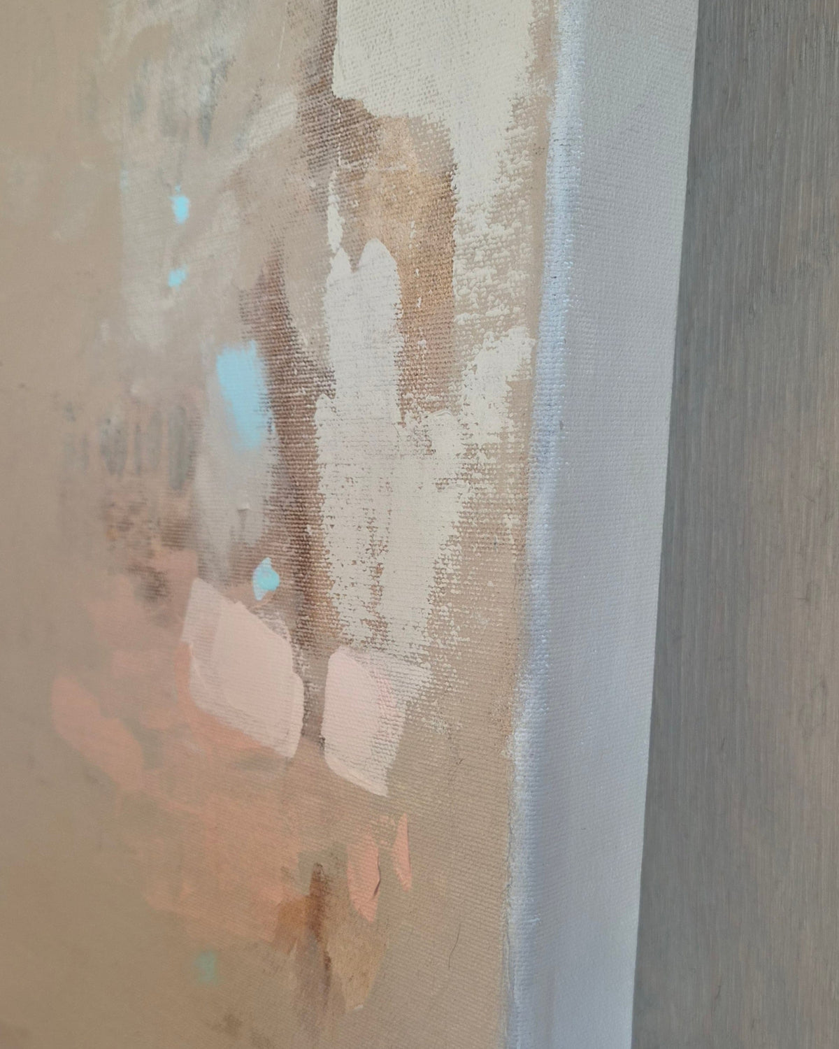 An abstract painting or art print featuring textured brushstrokes in beige, white, brown, and soft peach tones, shown close-up with a vertical white canvas edge on the right.