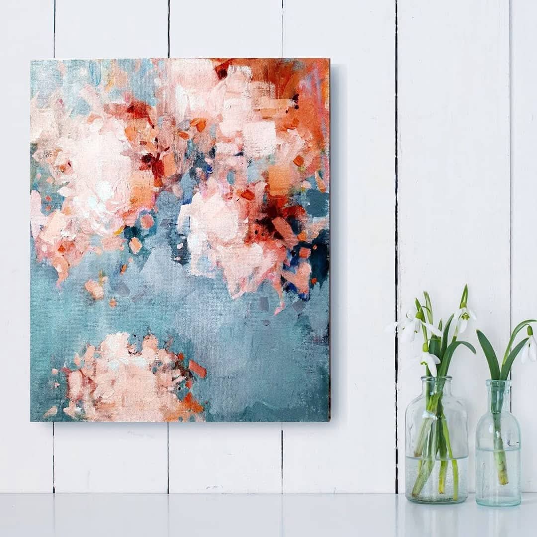 Abstract floral painting on a white wall with two glass bottles containing green plants.