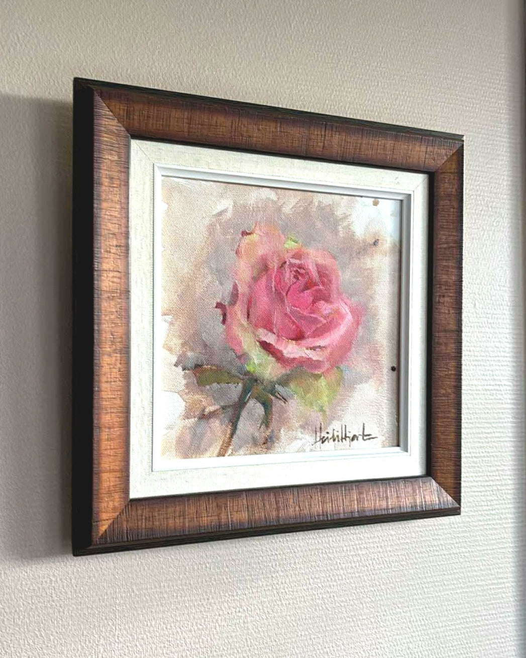 Framed artwork of a pink rose on a textured wall