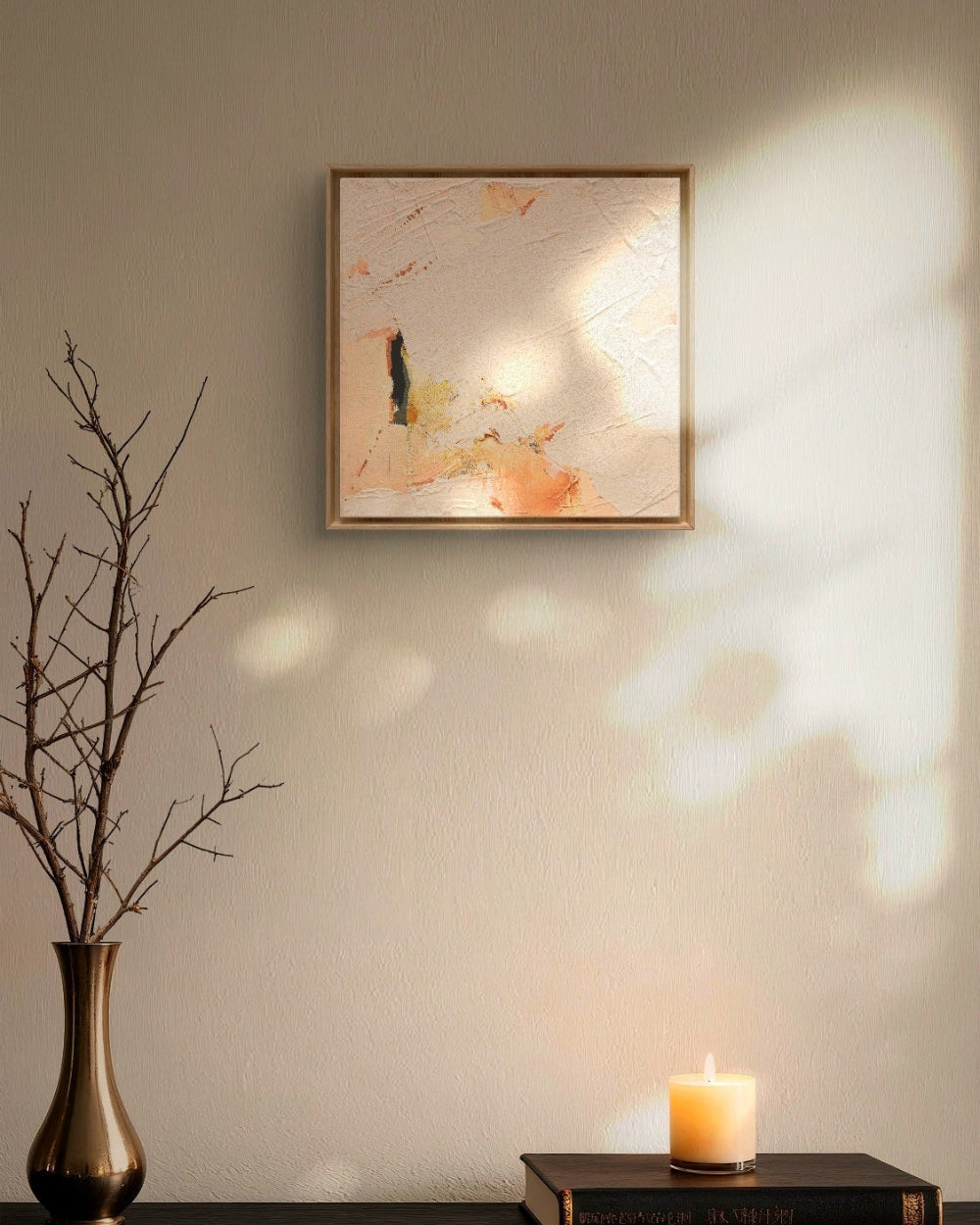 Framed artwork on a wall with a candle and vase on a table below.