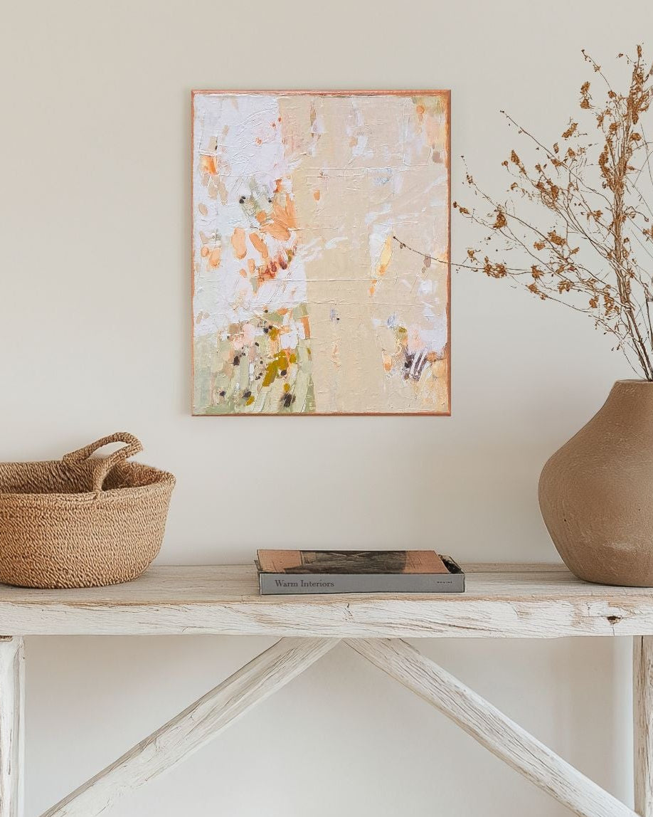 Nestled staircase with a wooden bench, woven basket, vase with dried plants, and floral painting on a white wall.