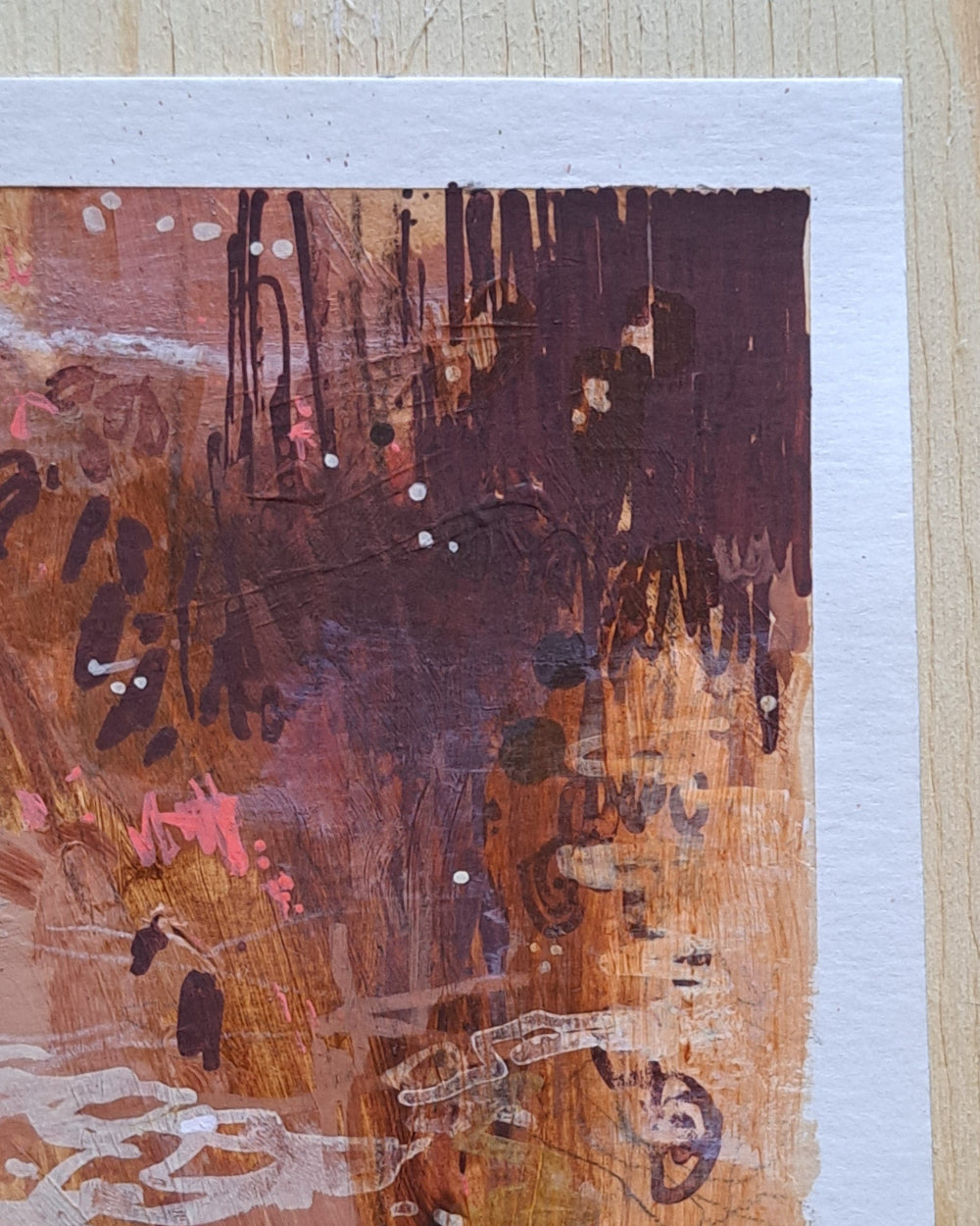 Abstract art piece with brown, pink, and black colors on a textured surface.