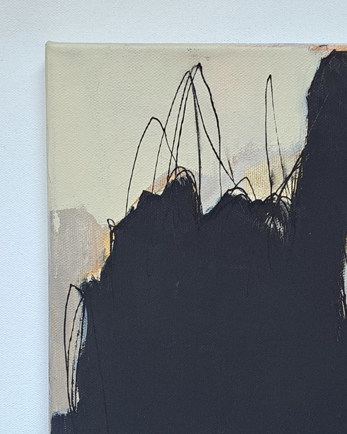 Closeup of abstract art piece with black and beige brush strokes on a light blue background