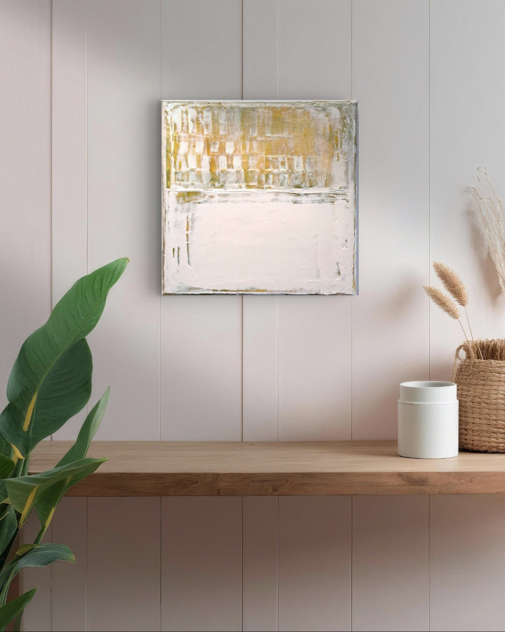 Abstract painting on a wall above a wooden shelf with decor items.